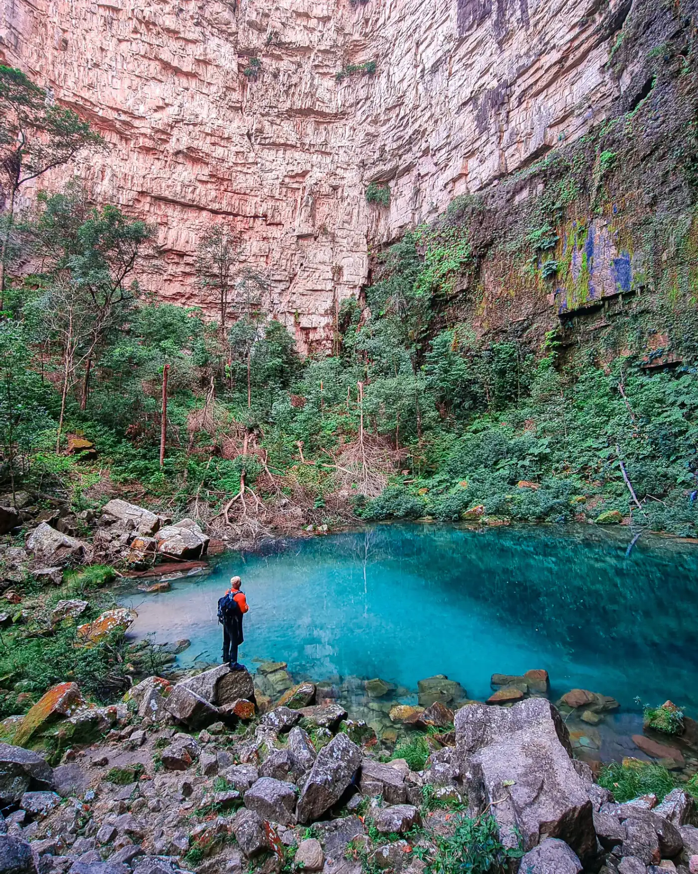 Cânion com lagoa de água azul cristalina e paredões avermelhados
